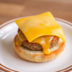 A stack of homemade Freezer Breakfast Sandwiches with eggs, cheese, and bacon on toasted English muffins, ready for storage or serving.